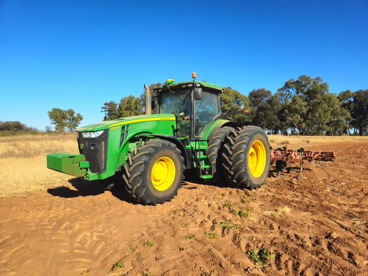 John Deere tractor with a cultivation implement in a field