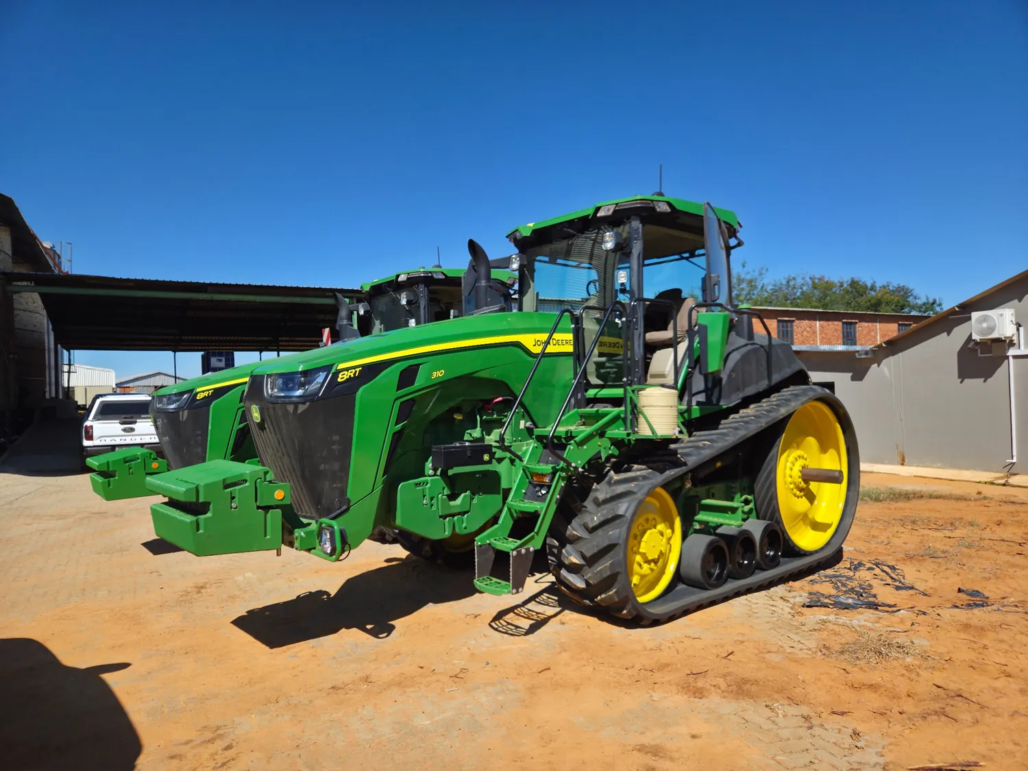 John Deere tracked tractor outside a workshop
