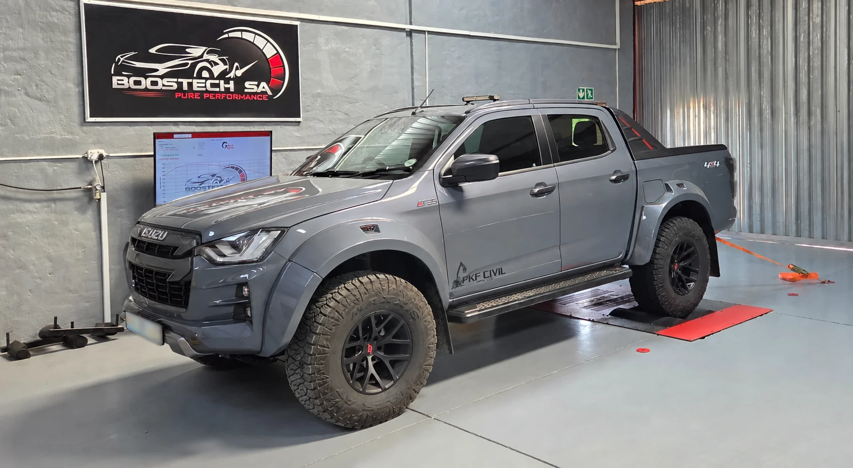 Grey Isuzu double-cab on the Boostech workshop dynamometer, with a test graph on the monitor
